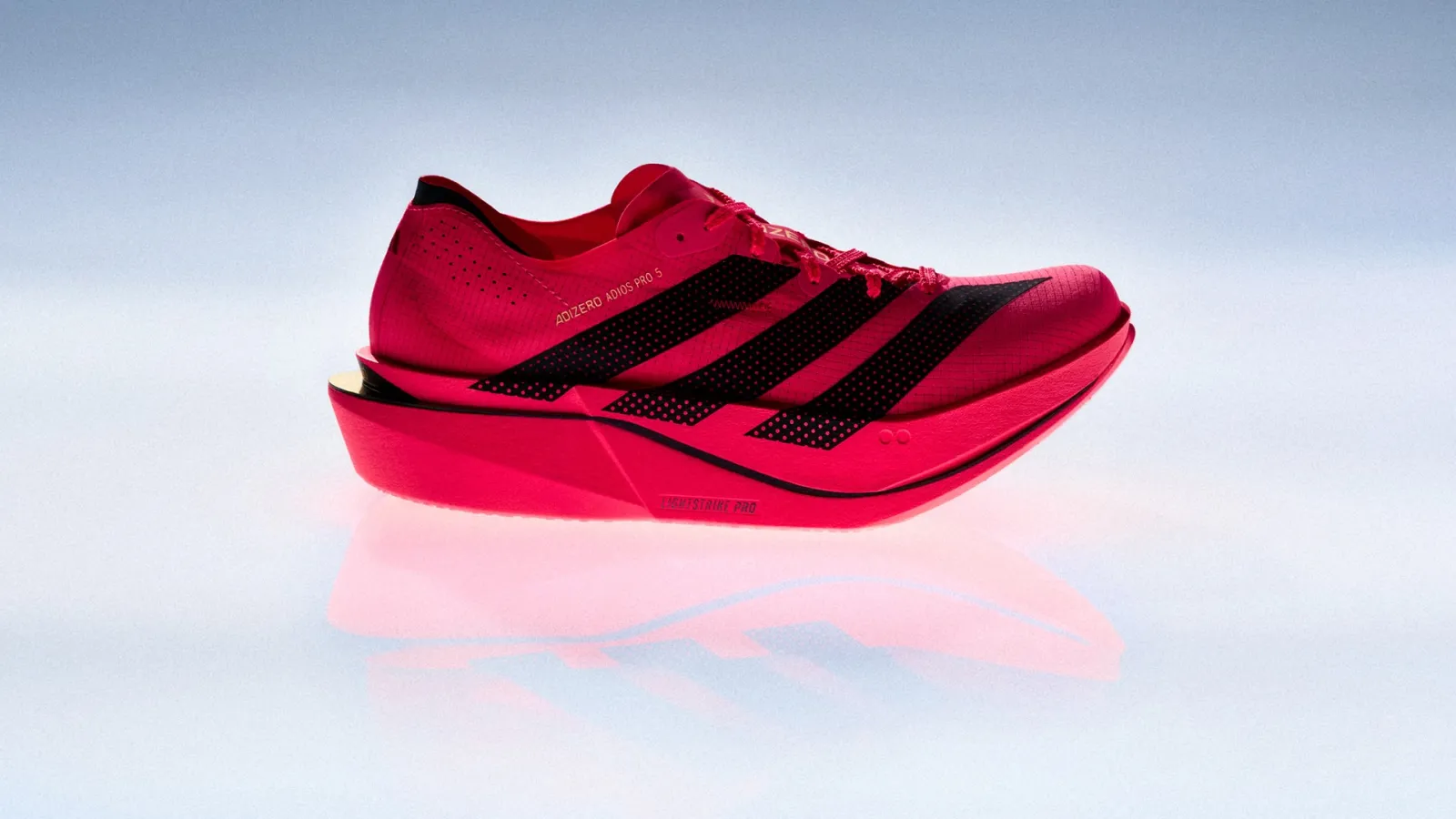 The red adidas Adizero Adios Pro 5 racing shoe on a glossy white surface