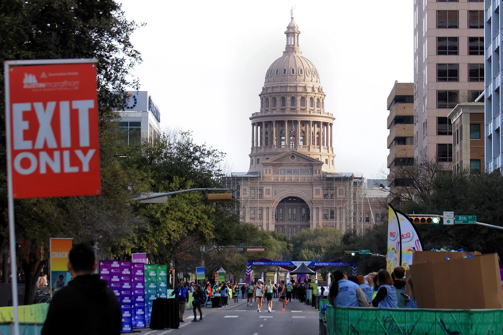 Finishers come down Congress Avenue toward the Austin Marathon finish arch, with the Texas State Capitol dome behind