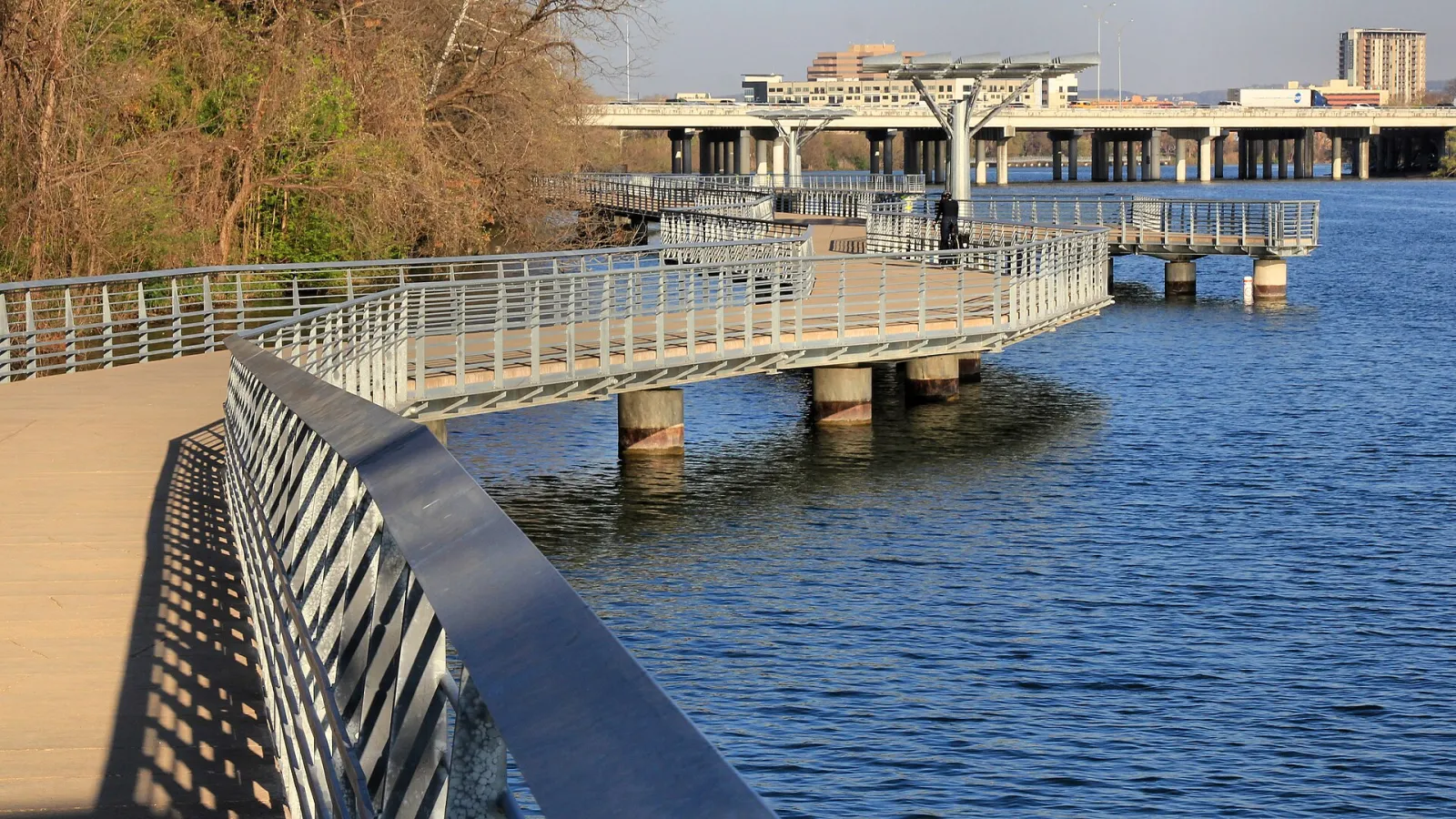 The curving boardwalk of the Butler Hike-and-Bike Trail over Lady Bird Lake in Austin, with the I-35 bridge in the background